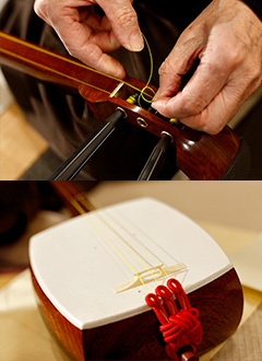 上／巧みな指さばきで、糸巻きに糸を結びつけていく。糸の太さは楽器のジャンルごとに異なる 下／絹ひもで作られているのが音緒（ねお）。ここに3本の糸を結びつける。皮と糸の間にあるのが駒。固定せずに、微妙に位置を変えて音を調整する