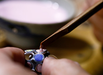 銀製の器体にへらを使って様々な色の釉薬を盛っていく。指輪づくりのワンシーン